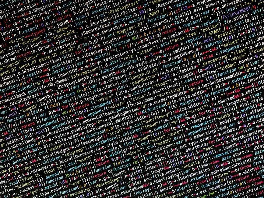 A person using a laptop on a wooden surface, focused on a screen displaying lines of HTML code with highlighted tags and attributes. The individual wears a wristwatch and their hand is positioned over